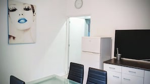 A room with a glass table, two black chairs, a white cabinet, and a television. - Laverie de François, wifi, commerce, 6pers, Aréna (Liévin)