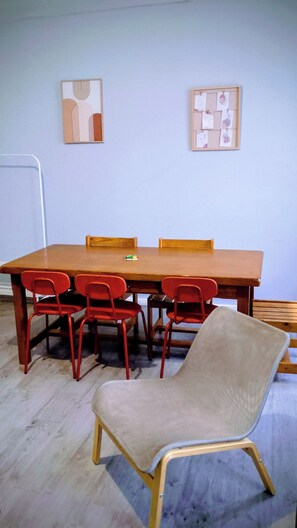 Ett konferensrum med ett träbord, röda stolar och en ensam beige stol. På väggen hänger två inramade konstverk.