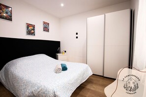 A bedroom with a bed, a nightstand, a wardrobe, and artwork on the wall. - Ready Player, jeux, wifi, proche Bollaert, 2 pers (Lens)