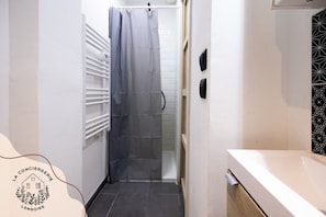 A narrow bathroom with a shower, a towel rack, and a white sink. - Ready Player, jeux, wifi, proche Bollaert, 2 pers (Lens)