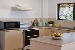 A kitchen with a microwave, stove, oven, and a bowl of fruit on the counter. - Anchorage Stay with Large Balcony, Marina Views & Parking Townsville (South Townsville)