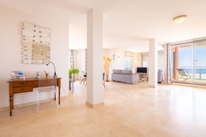 A spacious living area with a wooden desk, a clear chair, a sofa, and a television. - Magnificent Seafront Apartment (Valras-Plage)