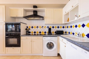 A kitchen with a microwave, oven, washing machine, and a sink. - Magnificent Seafront Apartment (Valras-Plage)
