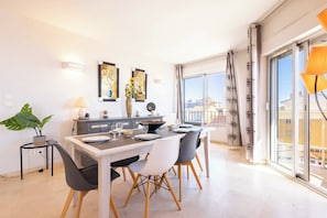 A modern dining area with a table set for four, a potted plant, and artwork on the wall. - Magnificent Seafront Apartment (Valras-Plage)