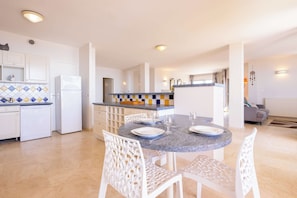 Una cocina moderna con armarios blancos, encimera de granito y comedor con mesa y sillas redondas.
