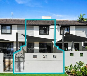 A two-story residential building with a tiled roof, a gated entrance, and outdoor umbrellas. - Central 2BR Stay - Walk to Strand & CBD w Parking (North Ward)