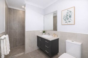 Une salle de bain moderne équipée d’une douche, d’un lavabo et de toilettes.