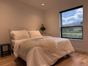 Een slaapkamer met een bed, een nachtkastje, een raam met uitzicht en een kleine tafel.