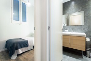 A bedroom with a bed, a bedside table, and a window with blinds. - The Collection - Centric 2BD Las Ramblas (Barcelona)