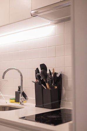 A kitchen with a modern design, featuring a black utensil holder, a stainless steel sink, and a white tiled backsplash. - Quiet Study · Selected Design (H09) (Providencia)