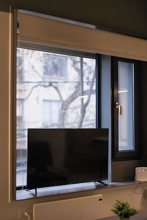 A television mounted on a wall with a window above it. - Quiet Study · Selected Design (H09) (Providencia)