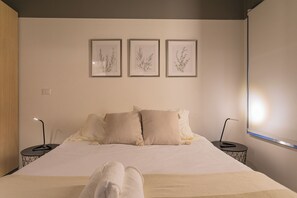 A hotel room with a bed, two bedside tables, and three framed botanical prints on the wall. - Quiet Study · Selected Design (H09) (Providencia)
