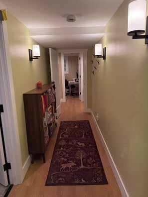 A hallway with a wooden bookshelf, a patterned rug, and a desk with a chair. - Beautiful and cozy 1-bedroom apartment in Greenwood neighborhood of Seattle (Seattle)