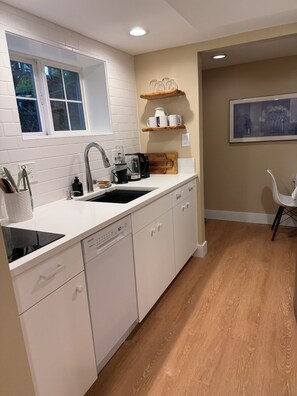 A modern kitchen with white cabinetry, a built-in dishwasher, and a window above the sink. - Beautiful and cozy 1-bedroom apartment in Greenwood neighborhood of Seattle (Seattle)
