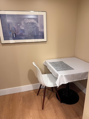 A dining area with a white table and chair, a framed picture on the wall, and a wooden floor. - Beautiful and cozy 1-bedroom apartment in Greenwood neighborhood of Seattle (Seattle)