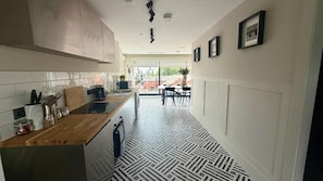 A modern kitchen with a wooden countertop, built-in cabinets, and a patterned floor. - Cozy Penthouse - 2 Bedroom in Central Manchester (Manchester)