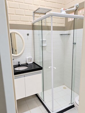 A modern bathroom with a glass-enclosed shower, a sink with a black countertop, and a mirror. - Cozy duplex in Porto de Galinhas, 50m from the sea. • Pool • Grill (Ipojuca)