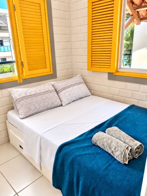 A bed with two pillows, a blue blanket, and a rolled-up towel. - Cozy duplex in Porto de Galinhas, 50m from the sea. • Pool • Grill (Ipojuca)