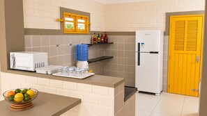 A kitchen with a microwave, a water dispenser, a refrigerator, and a fruit bowl. - Cozy duplex in Porto de Galinhas, 50m from the sea. • Pool • Grill (Ipojuca)