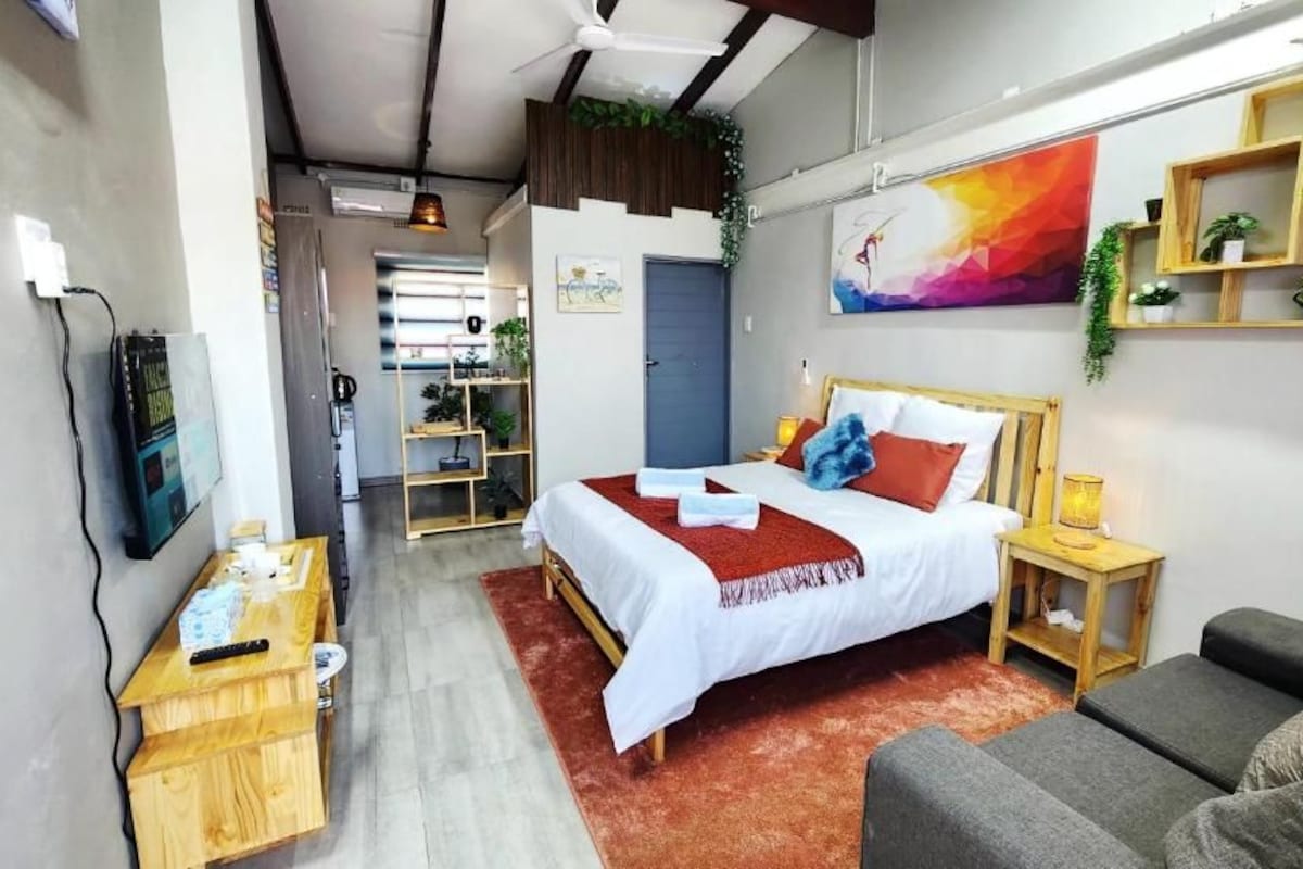 Een moderne slaapkamer met een bed, nachtkastjes, een bank en een televisie.