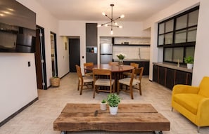 A modern living room with a dining table, chairs, a yellow sofa, and a wooden coffee table. - 3-Bedroom Apartment with AC Near the Zócalo (Oaxaca de Juárez)