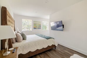 A bedroom with a bed, a TV mounted on the wall, and a window with blinds. - Modern Oasis 3-bedroom house with AC in quiet Houston neighborhood (Houston)
