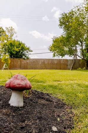 A mushroom in a garden with a wooden fence and trees in the background. - Modern Oasis 3-bedroom house with AC in quiet Houston neighborhood (Houston)