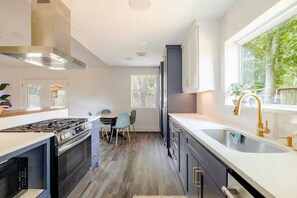 A modern kitchen with a gas stove, oven, and a large window providing natural light. - Modern Oasis 3-bedroom house with AC in quiet Houston neighborhood (Houston)