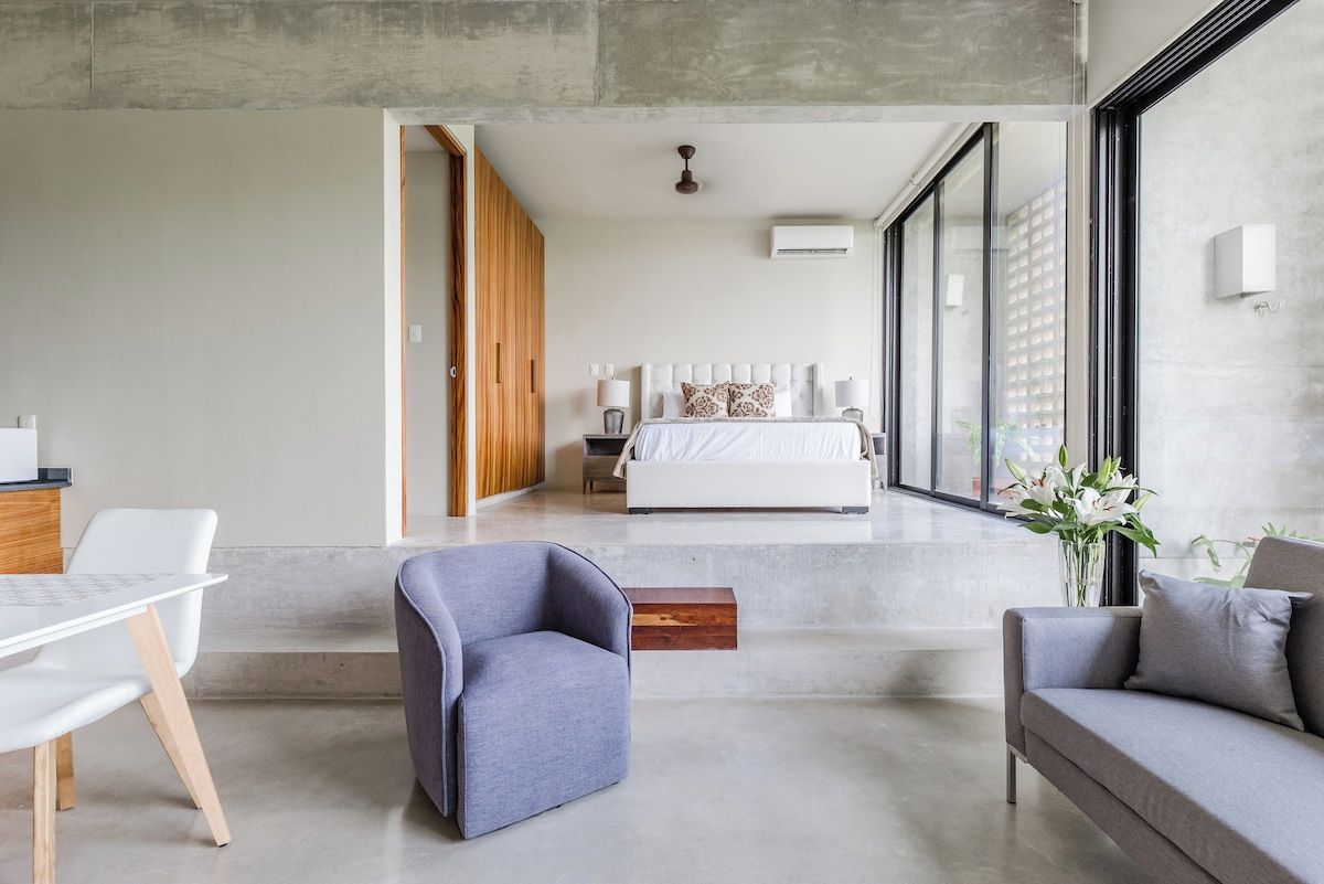 A modern bedroom with a large bed, bedside lamps, and a view through a glass door.