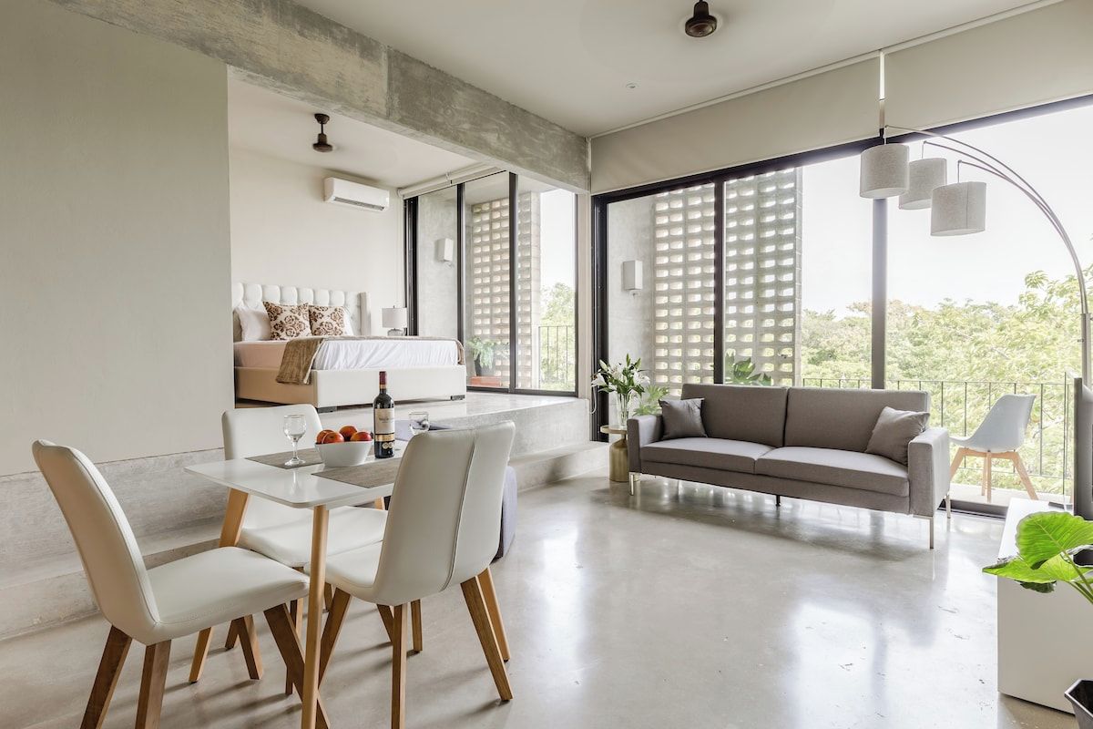 Uma sala de estar moderna com área de jantar, janelas amplas e um sofá.