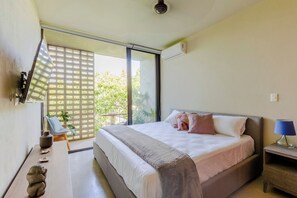 A bedroom with a bed, a nightstand, a lamp, a TV, and a window with a view of greenery. - Huachinango 34 by Homirent (Cancún)