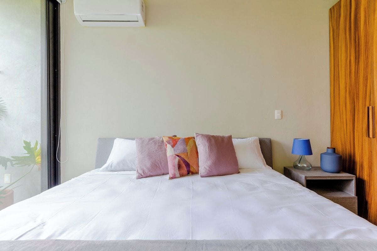 A hotel room with a bed, a nightstand, a lamp, and a wardrobe.