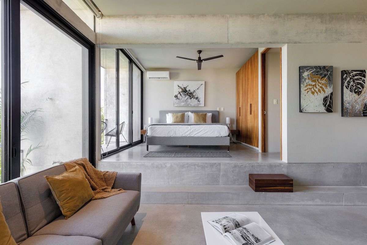 Quarto moderno com cama, ventilador de teto e obras de arte nas paredes.
