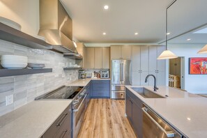 A modern kitchen with a central island, built-in oven, and stainless steel appliances. - Big Sky Luxury: Modern 4BR, Heated Patio, Fire Pit, Hot Tub, Views, Walk to Town (Big Sky)