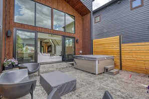 Een modern terras buiten met een bank, stoelen en een jacuzzi.