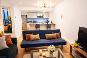 A modern living room with a blue sofa, a coffee table with candles, and a TV.