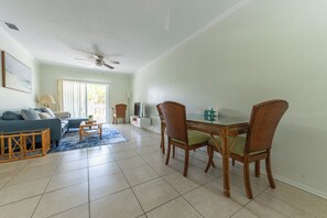 A living room with a sofa, coffee table, dining table with chairs, and a ceiling fan. - Coastal 2BR on the Canal near Anna Maria (Bradenton)