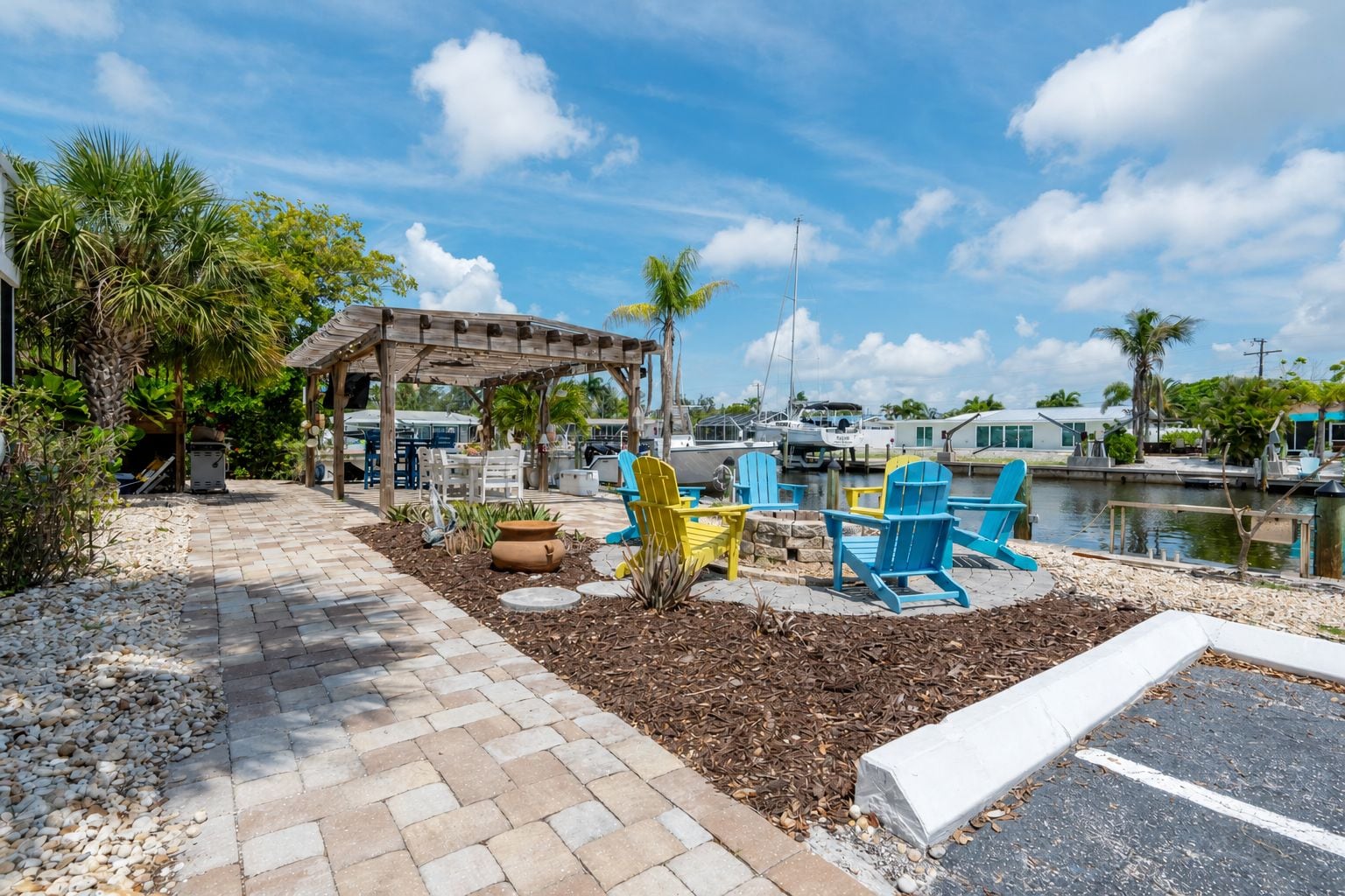 Une terrasse au bord de l’eau, avec des sièges d’extérieur, une pergola et une marina en arrière-plan.