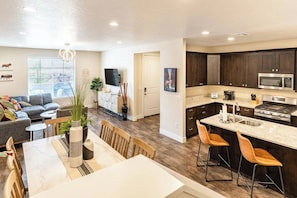 Une cuisine moderne avec des meubles de couleur sombre, un four à micro-ondes en acier inoxydable et un grand îlot central doté de tabourets de bar.