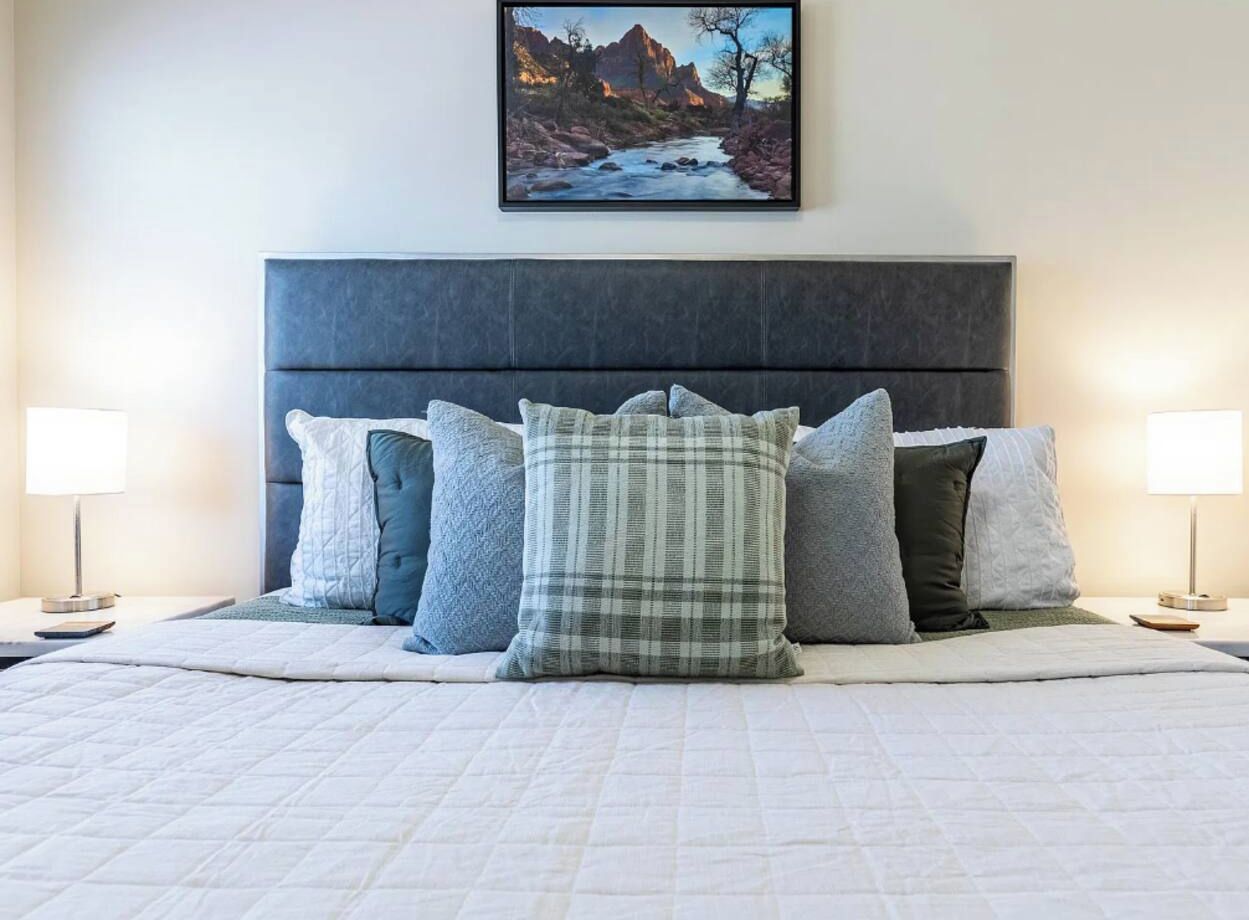 Sink into soft bedding and plush pillows, with warm bedside lighting and Zion-inspired artwork adding a peaceful touch.