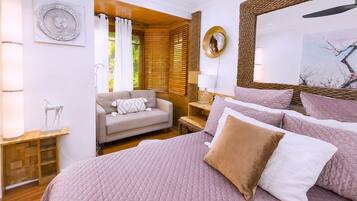 A bedroom with a large bed, a sofa, a bedside table, a lamp, and a mirror.
