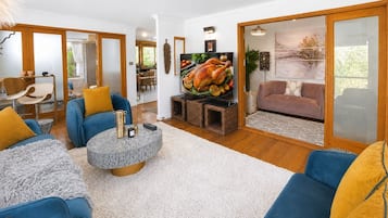 Una sala de estar moderna con un sofá azul, una mesa de centro y un televisor que muestra un pavo asado.