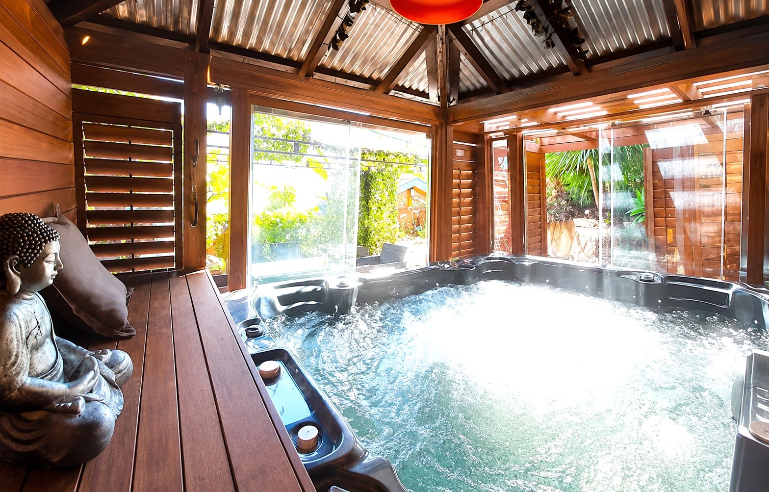 Ein Whirlpool mit einer Holzterrasse und einer Buddha-Statue.