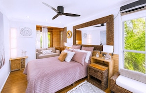 Een slaapkamer met een bed, nachtkastje, lamp en een plafondventilator.