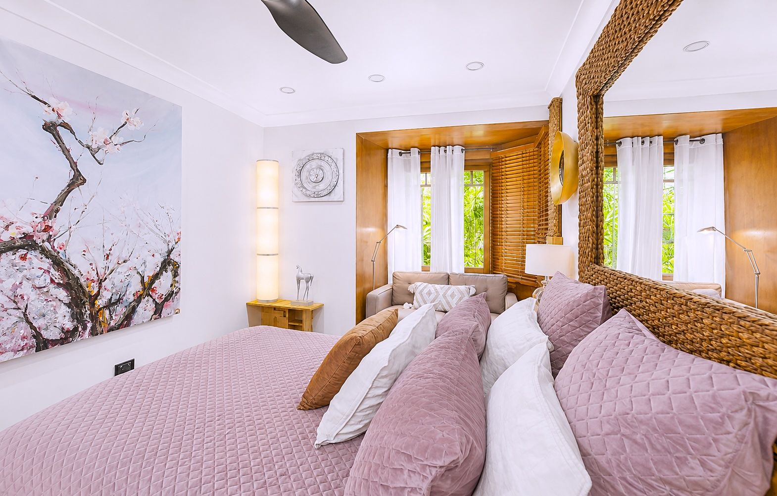 Un dormitorio con una cama grande, un reloj en la pared y un ventanal con cortinas.