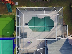 An aerial view of a building with a large open space, possibly a pool area, surrounded by a metal framework. - Private Pool, Pickleball, Mini Golf, Game Room (Bradenton)