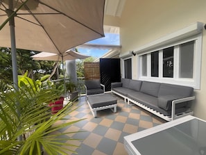 An outdoor seating area with a sofa and chairs, a glass table, and a checkered floor. - Charming duplex with swimming pool (Saint-François)