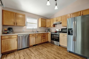 A modern kitchen with wooden cabinets, stainless steel appliances, and a dishwasher. - 3BR 2 Bath Ranch-style house in Salida - Sleeps 7 (Salida)