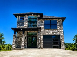 A two-story house with a stone facade, large windows, and a garage.