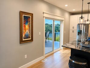 A kitchen with a large island, a sliding glass door leading to a deck, and a framed painting on the wall.